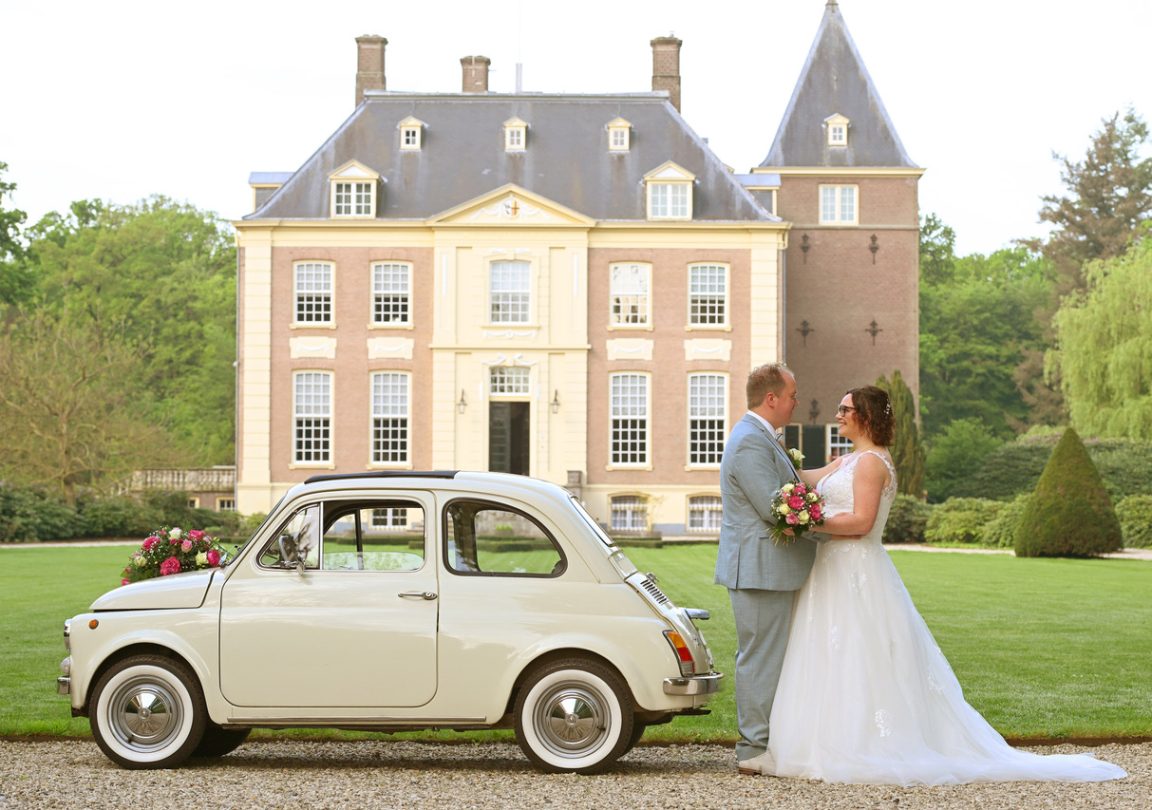 Fotocaroussel. Bruidspaar staat voor Huis Verwolde in Laren, met links van hen de Bruiloftauto.