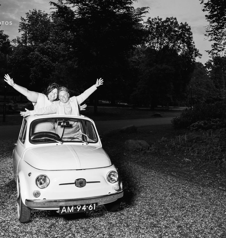 Fotocaroussel. Bruidspaar staat juichend in trouwauto met opendak.